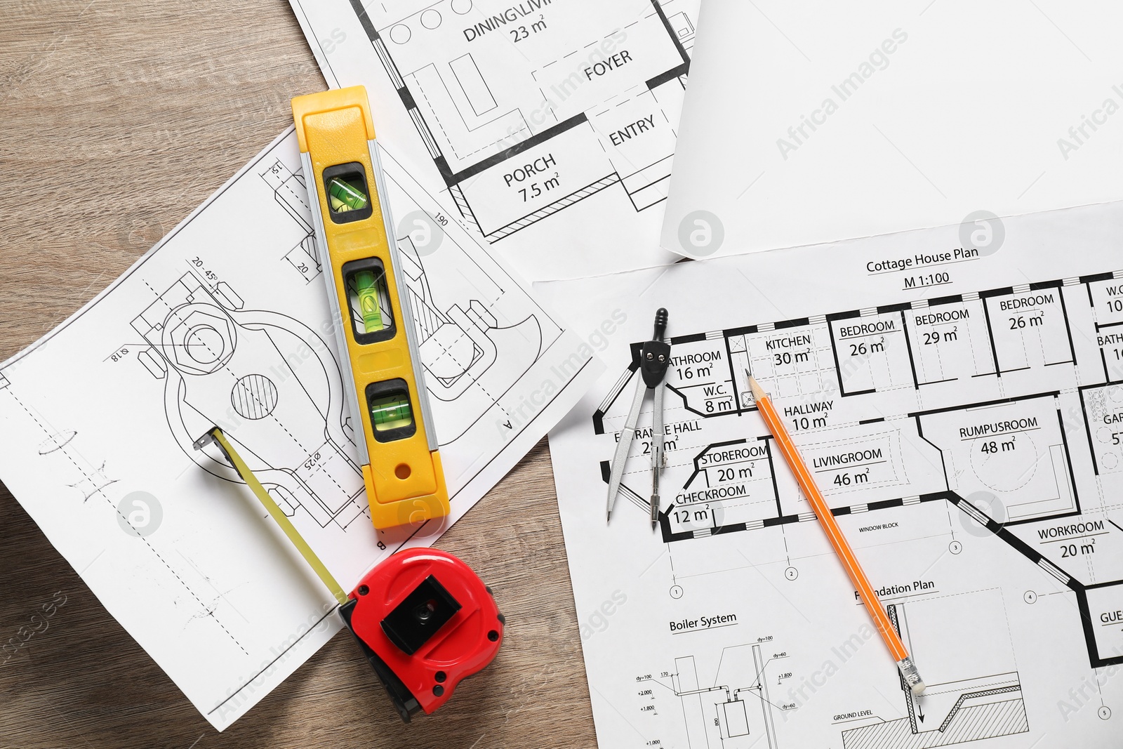 Photo of Different engineering drawings, building level, measuring tape, pencil and dividers on wooden table, flat lay