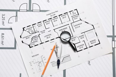 Photo of Magnifying glass, pensil and dividers on different engineering drawings, top view