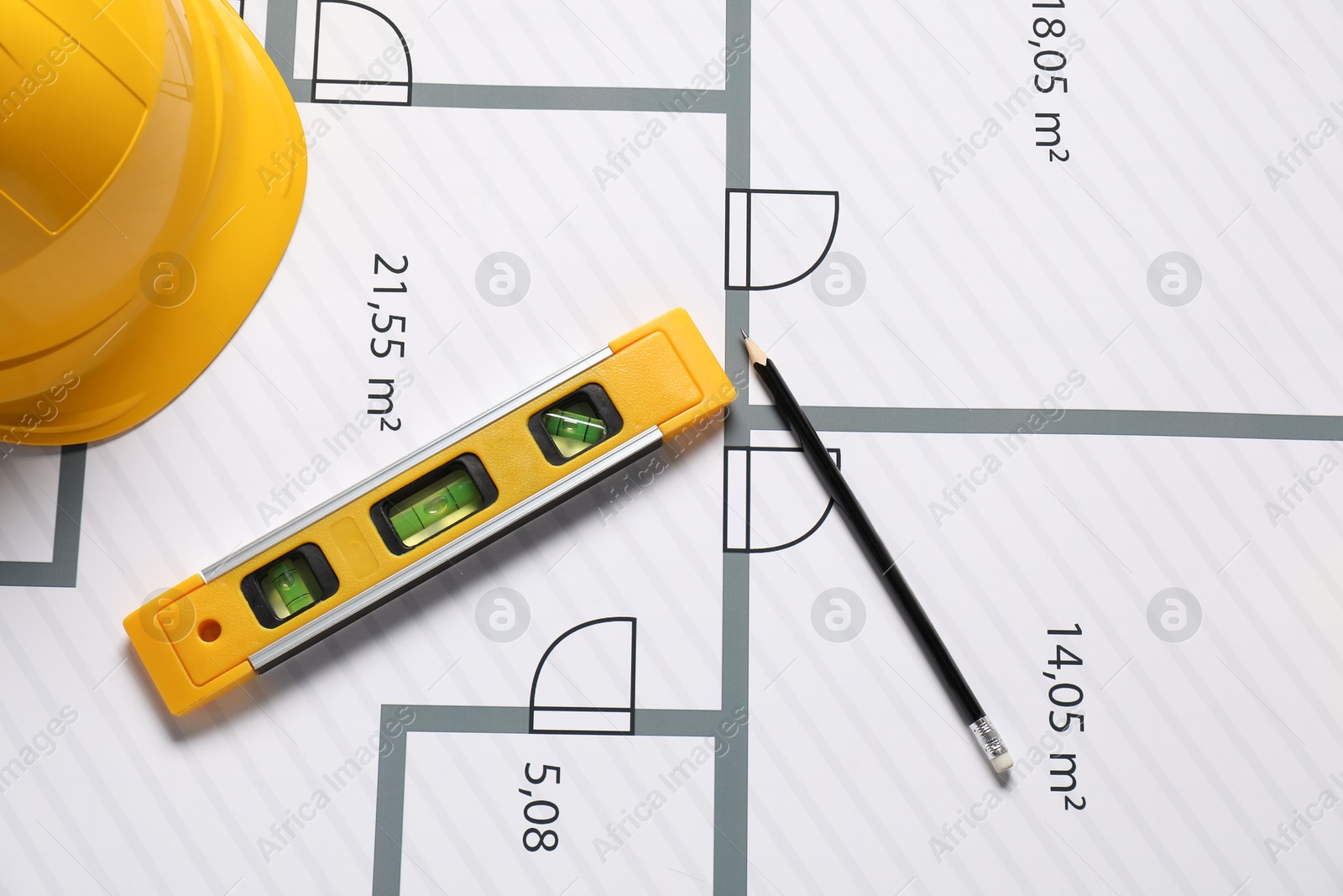 Photo of Pencil, hard hat and building level on different architectural drawings, top view