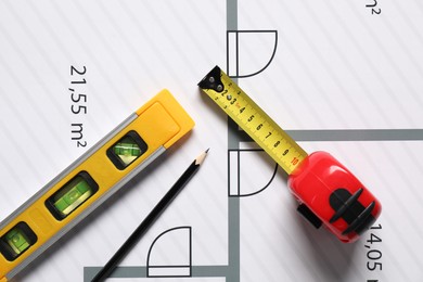 Photo of Pencil, measuring tape and building level on different architectural drawings, top view