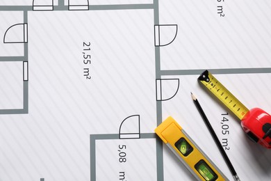 Photo of Pencil, measuring tape and building level on different architectural drawings, top view