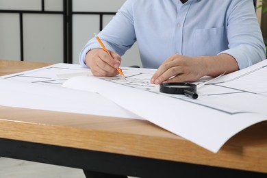 Photo of Architect working with project at wooden table in office, closeup