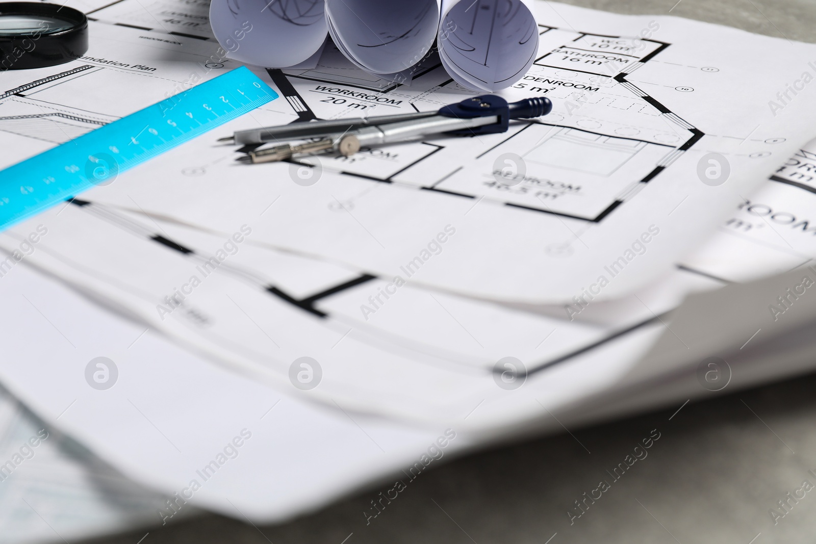 Photo of Different architectural drawings, divider and ruler on grey table, closeup