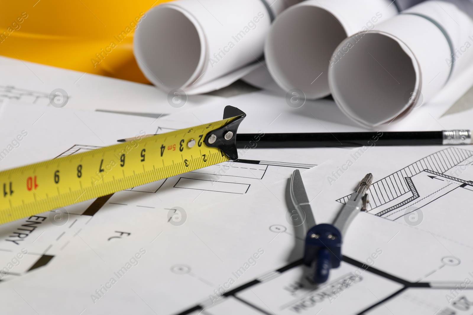 Photo of Different engineering drawings, pencil, divider and measuring tape on table