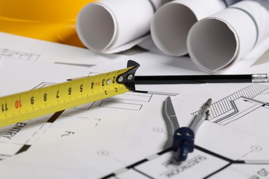 Photo of Different engineering drawings, pencil, divider and measuring tape on table