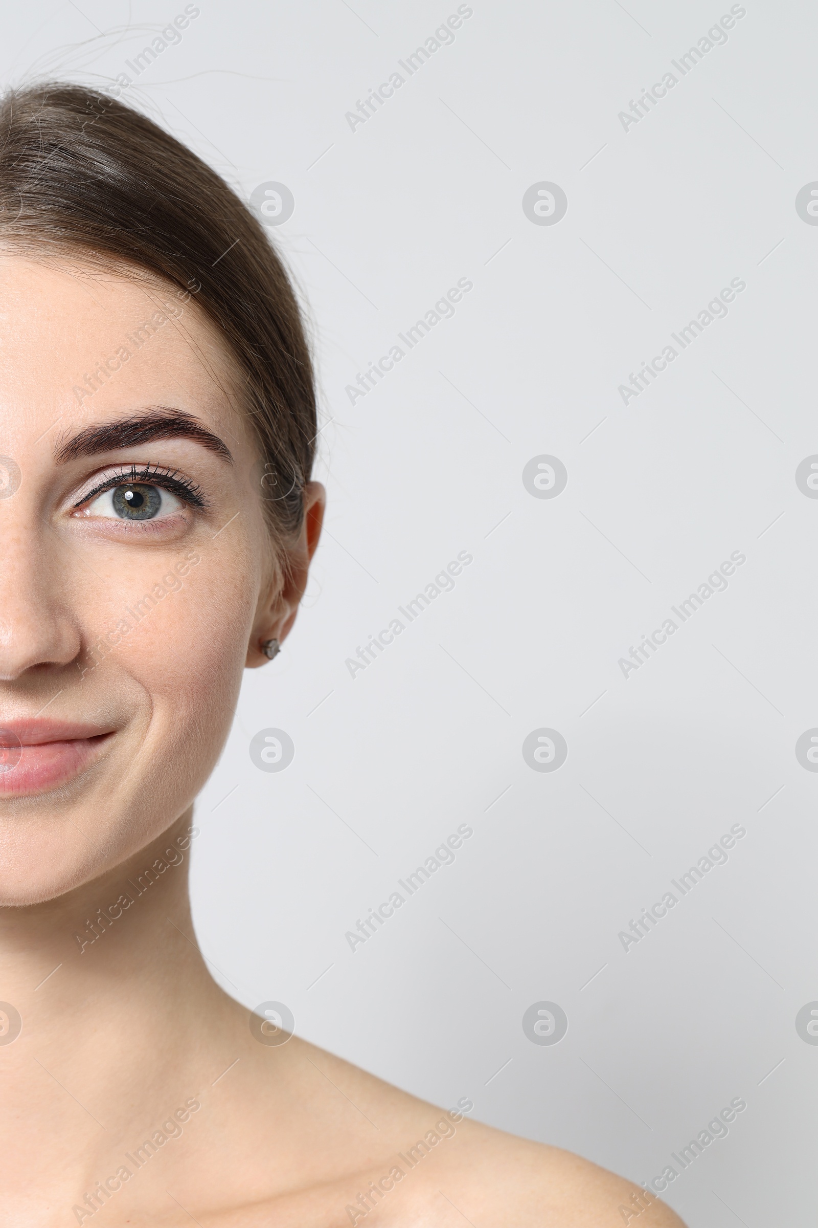 Photo of Beautiful young woman after henna eyebrows dyeing on light background, closeup