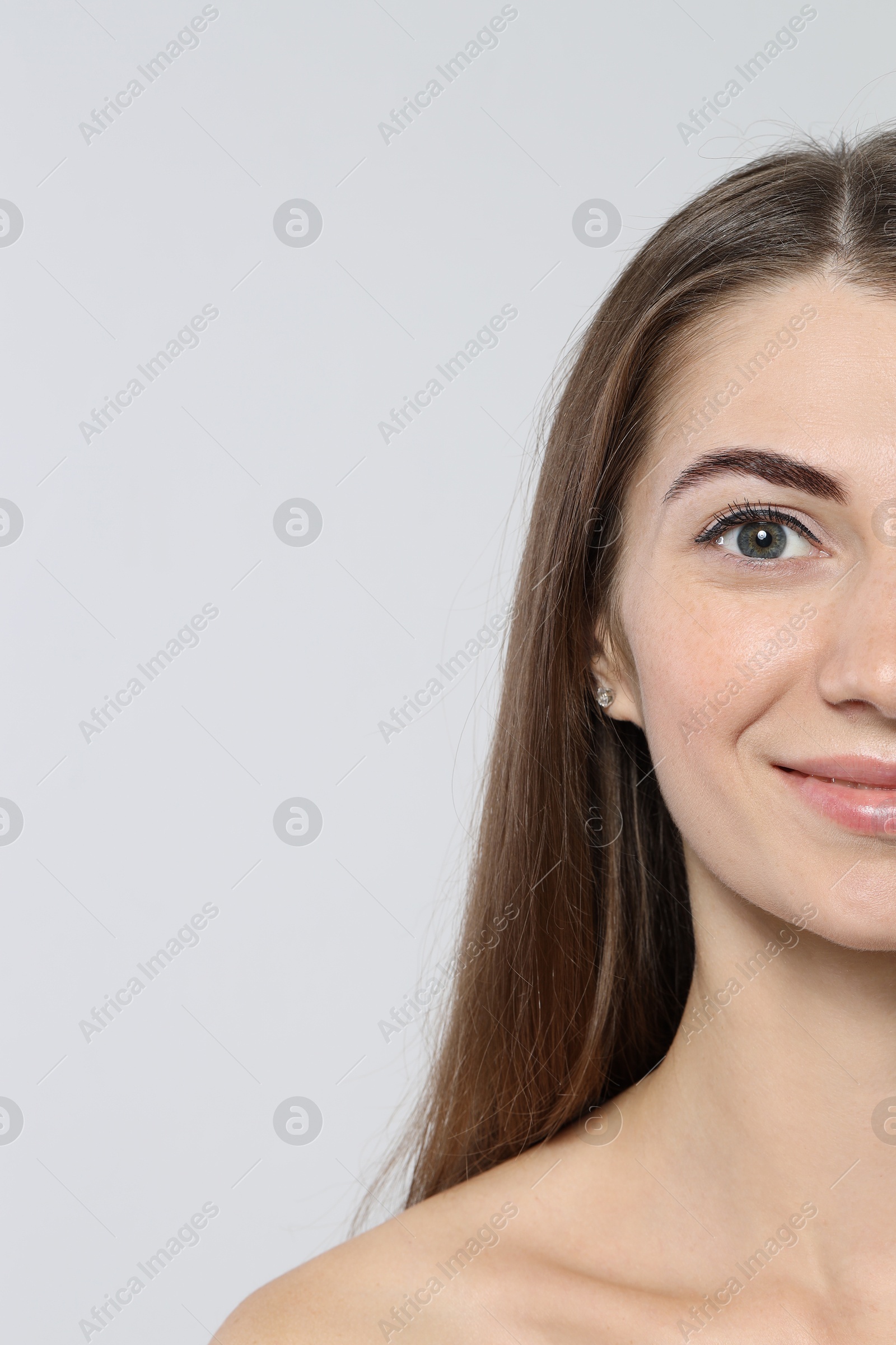 Photo of Beautiful young woman after henna eyebrows dyeing on light background, closeup. Space for text