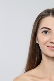 Photo of Beautiful young woman after henna eyebrows dyeing on light background, closeup. Space for text