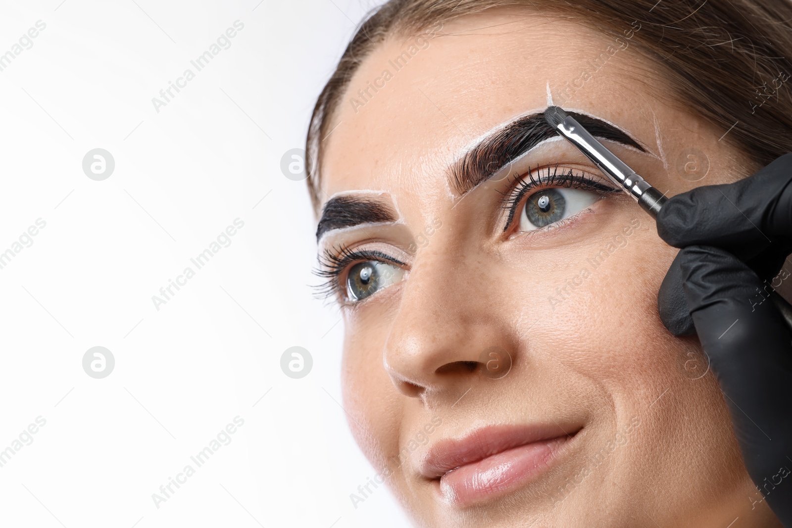 Photo of Young woman undergoing henna eyebrows dyeing on light background, closeup. Space for text