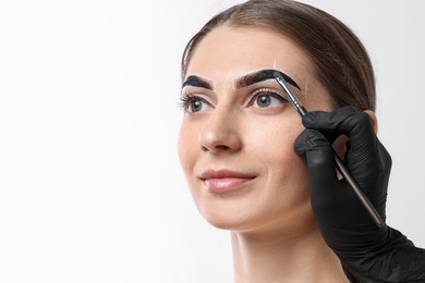 Photo of Young woman undergoing henna eyebrows dyeing on light background, closeup. Space for text