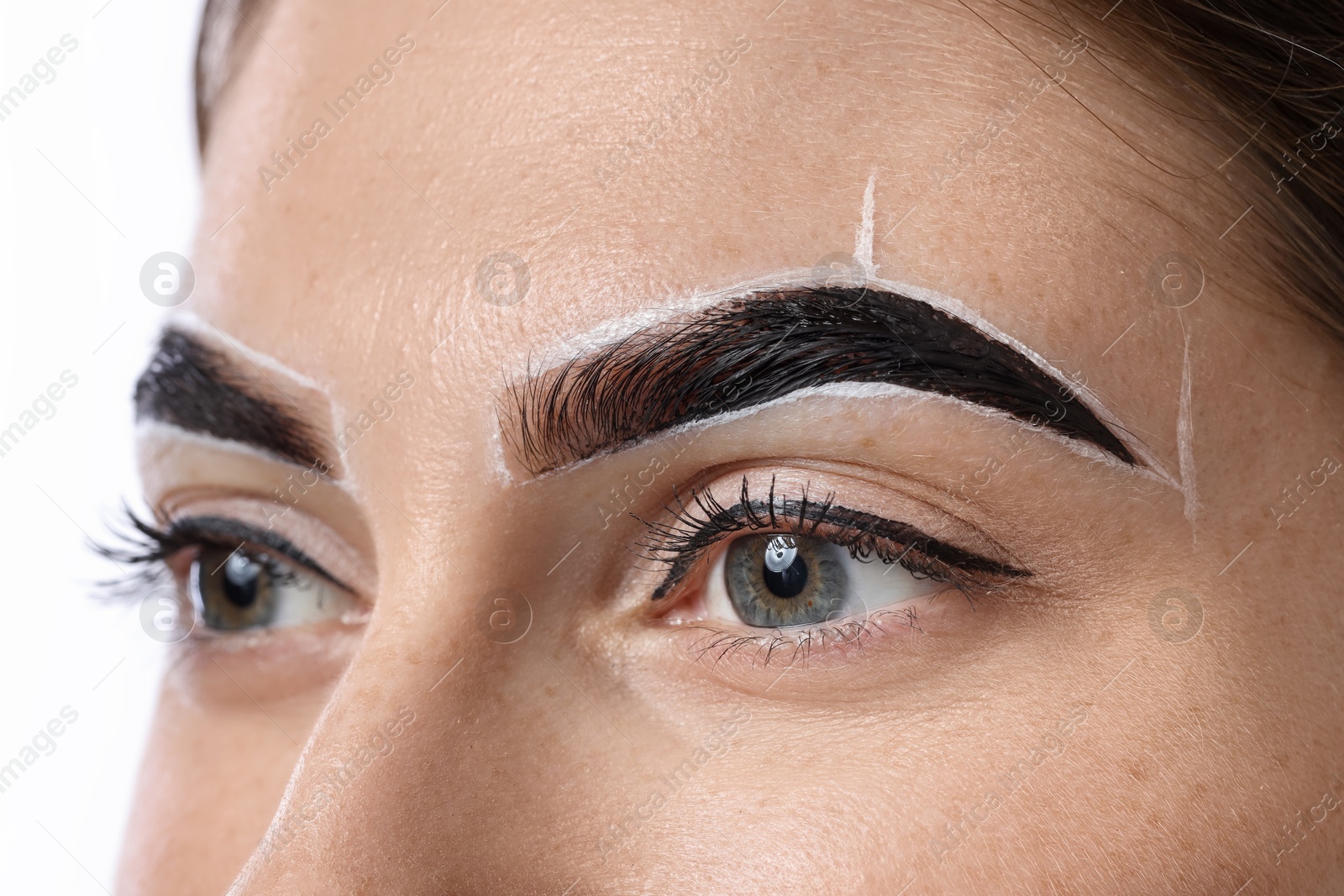 Photo of Young woman during henna eyebrows dyeing procedure on light background, closeup