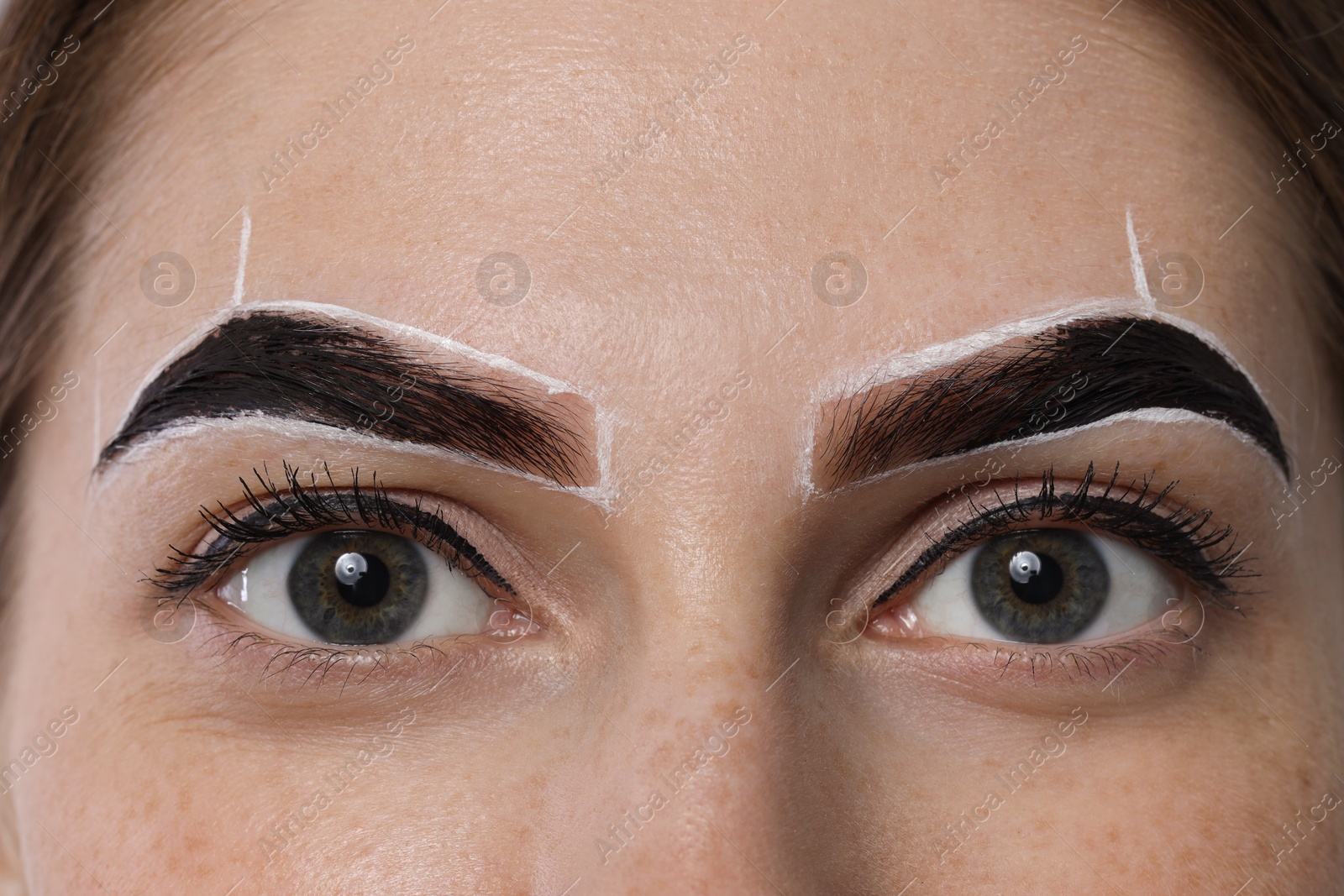 Photo of Young woman during henna eyebrows dyeing procedure, closeup