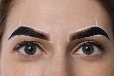 Photo of Young woman during henna eyebrows dyeing procedure, closeup