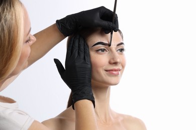 Photo of Young woman undergoing henna eyebrows dyeing procedure on white background