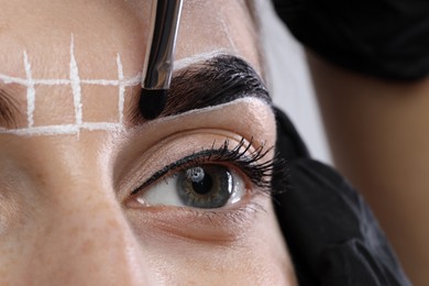 Photo of Young woman undergoing henna eyebrows dyeing procedure, closeup