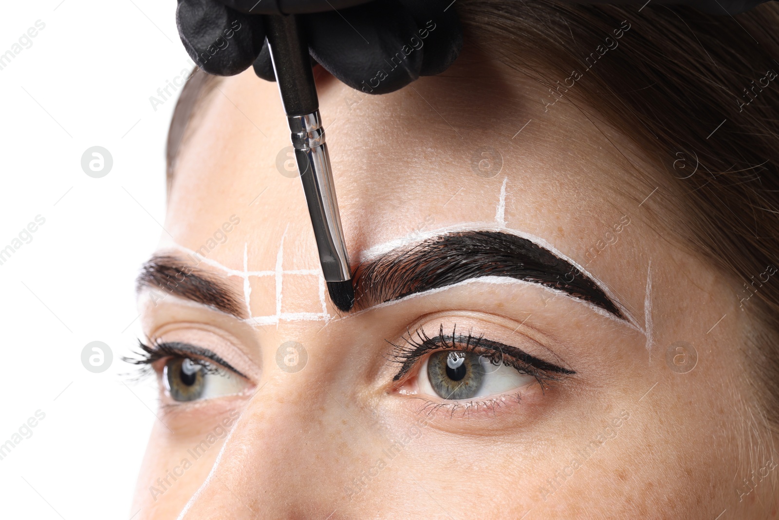 Photo of Young woman undergoing henna eyebrows dyeing on light background, closeup