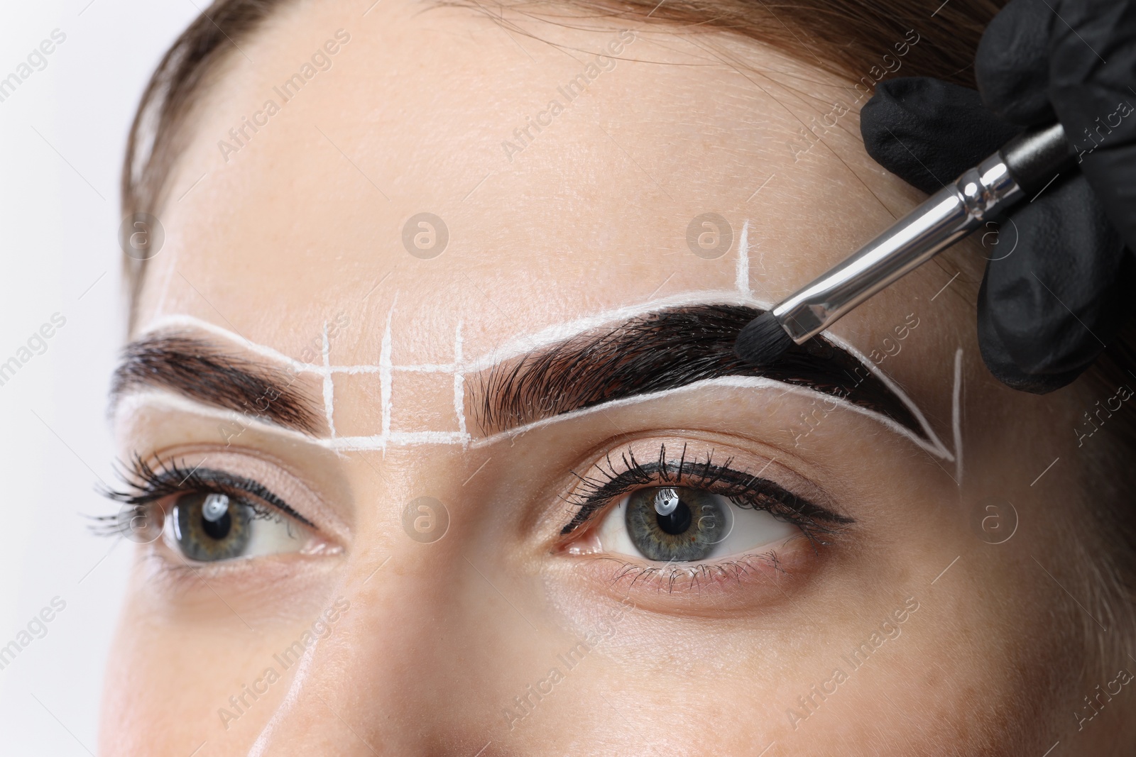 Photo of Young woman undergoing henna eyebrows dyeing procedure, closeup