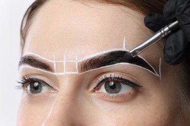 Young woman undergoing henna eyebrows dyeing procedure, closeup