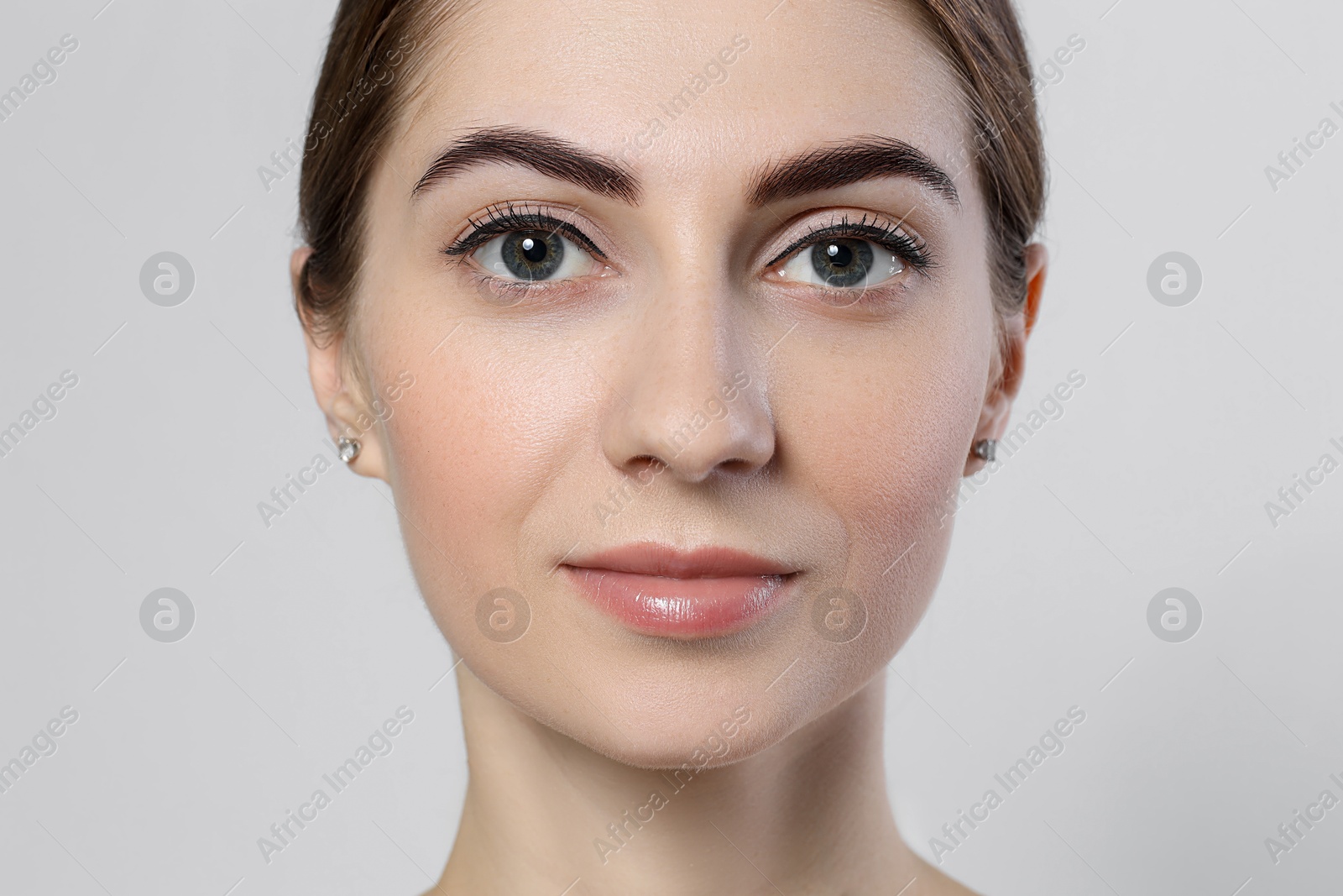 Photo of Beautiful young woman after henna eyebrows dyeing on light background, closeup