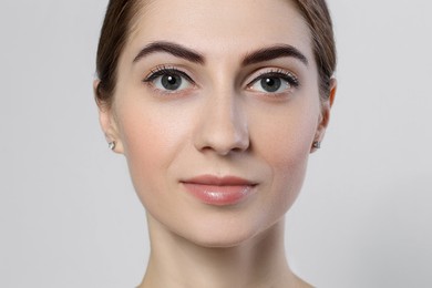 Photo of Beautiful young woman after henna eyebrows dyeing on light background, closeup