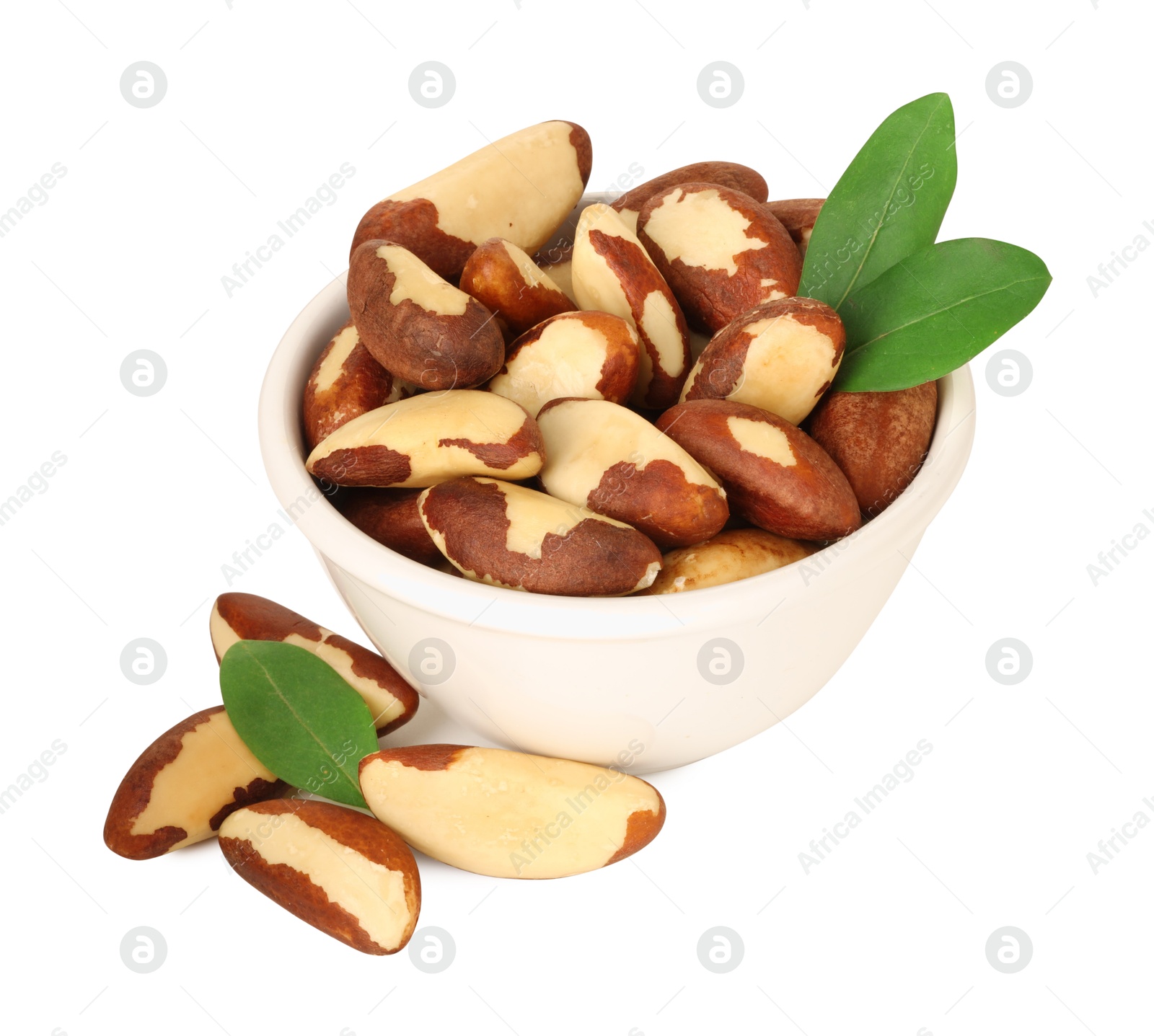 Photo of Tasty Brazil nuts in bowl and green leaves isolated on white