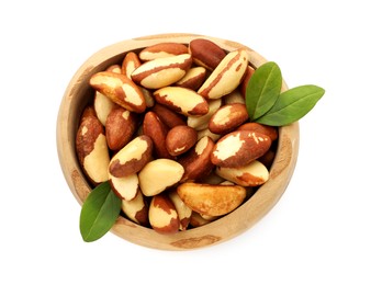 Photo of Tasty Brazil nuts and green leaves in bowl isolated on white, top view