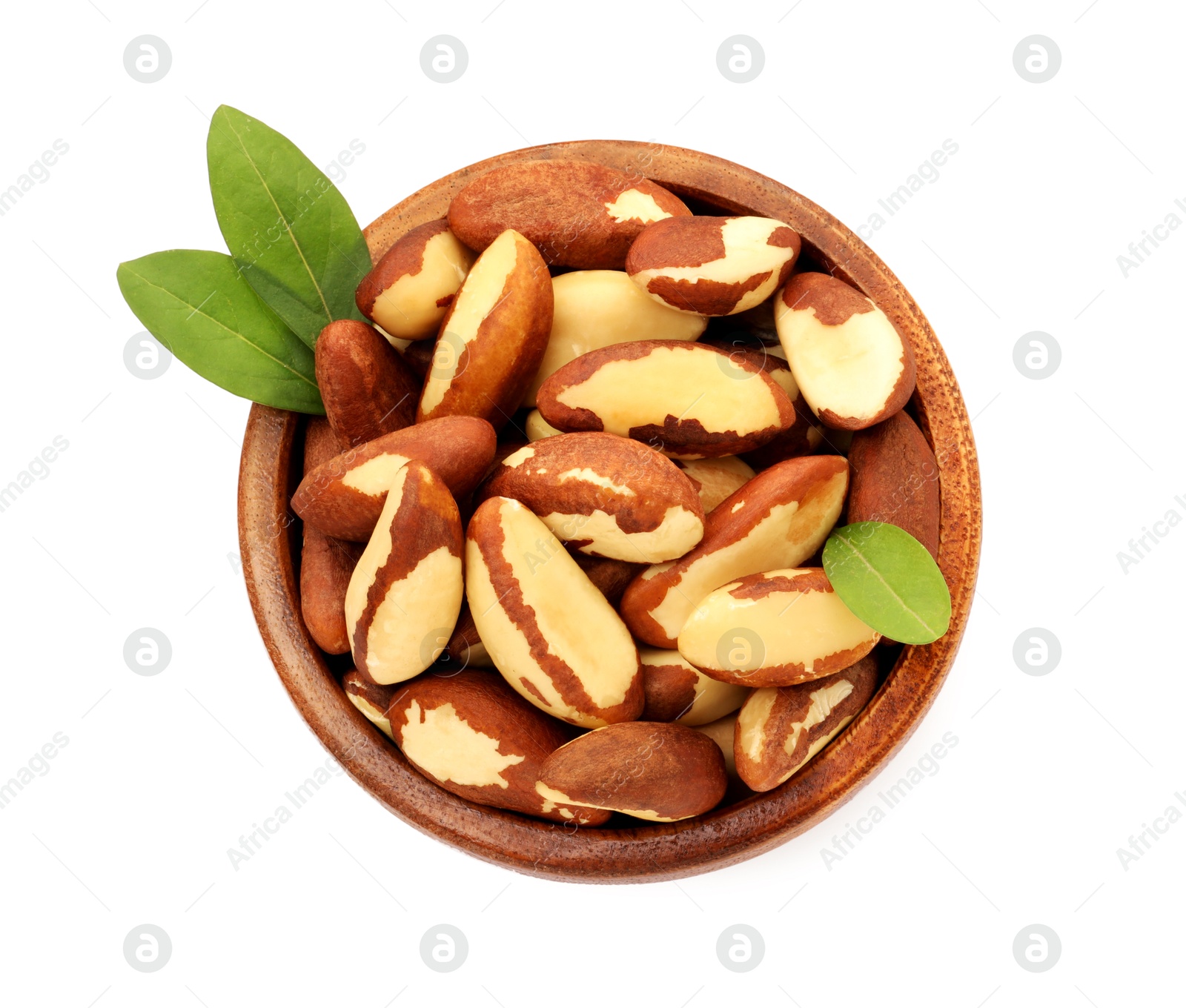 Photo of Tasty Brazil nuts and green leaves in bowl isolated on white, top view