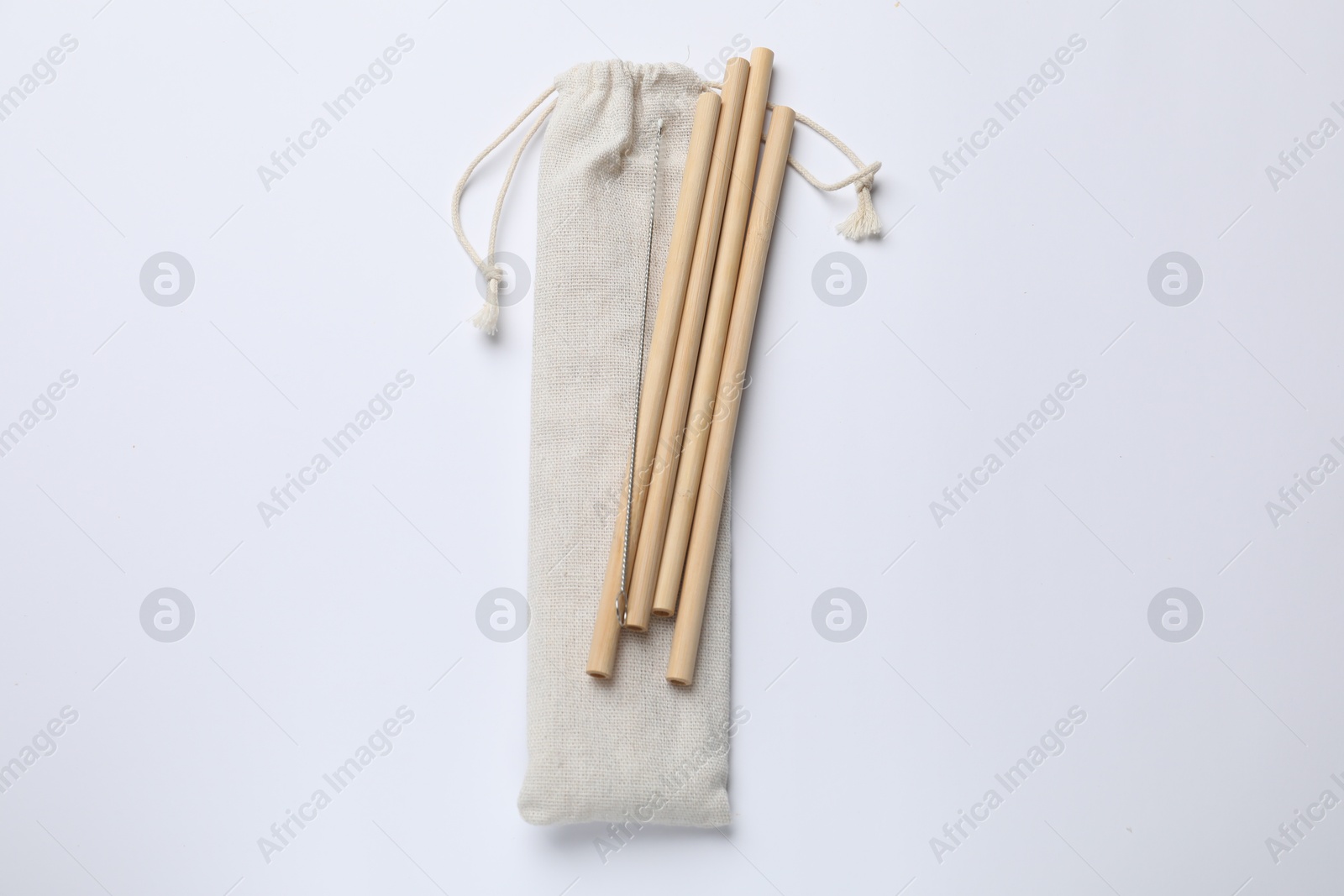 Photo of Bamboo drinking straws, cleaning brush and bag on white background, top view