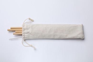 Photo of Bamboo drinking straws and cleaning brush in bag on white background, top view