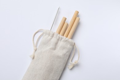 Photo of Bamboo drinking straws and cleaning brush in bag on white background, top view