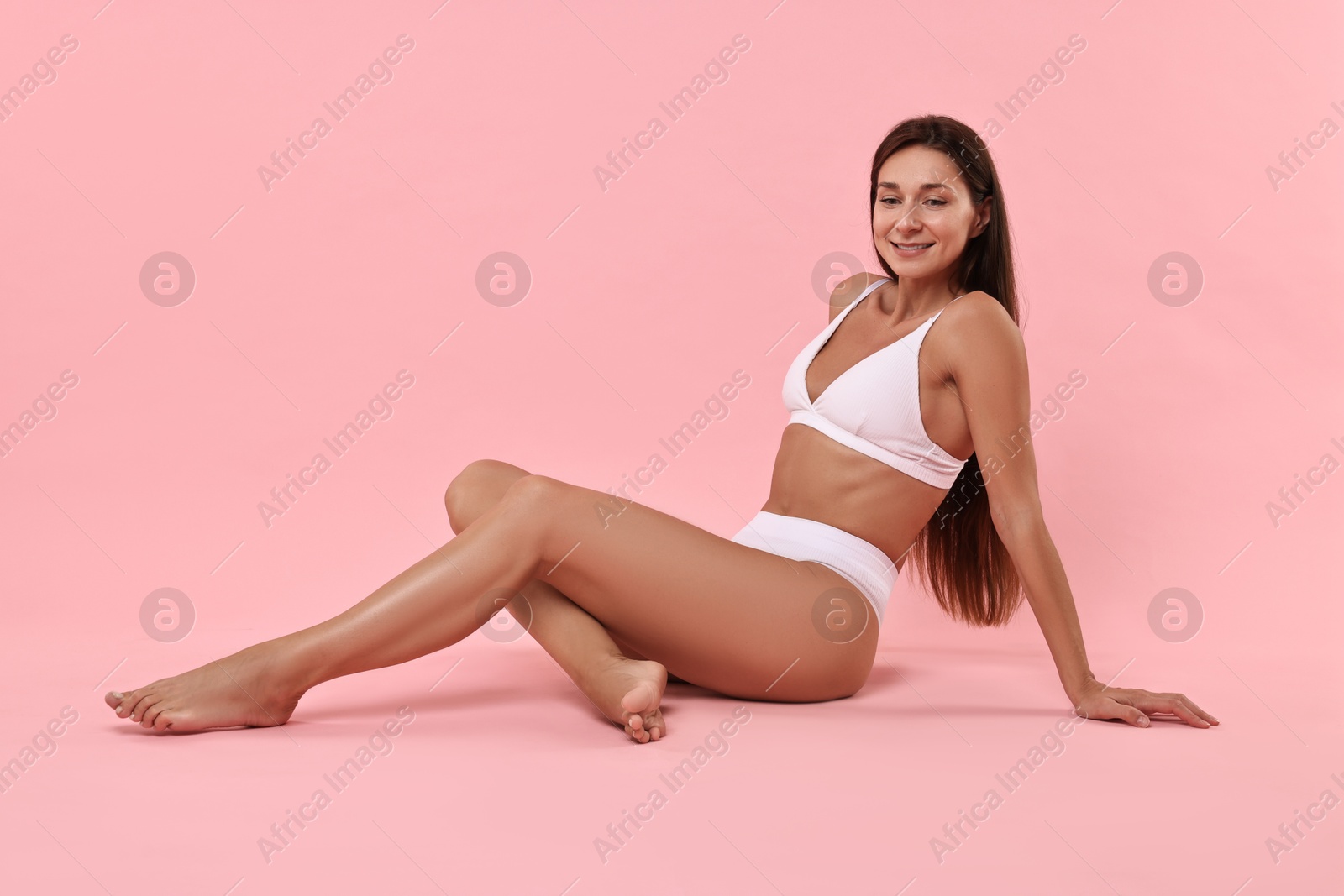 Photo of Smiling woman with perfect skin posing on pink background. Body care