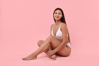 Photo of Smiling woman with perfect skin posing on pink background. Body care