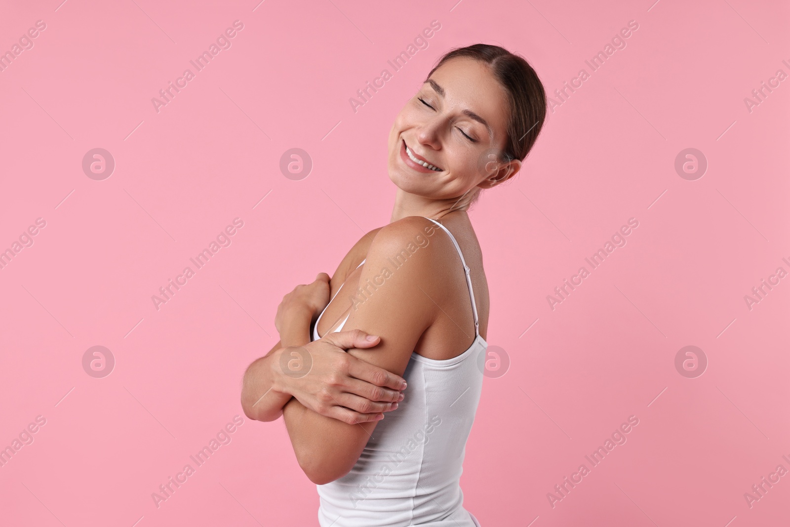 Photo of Smiling woman with perfect skin on pink background. Body care