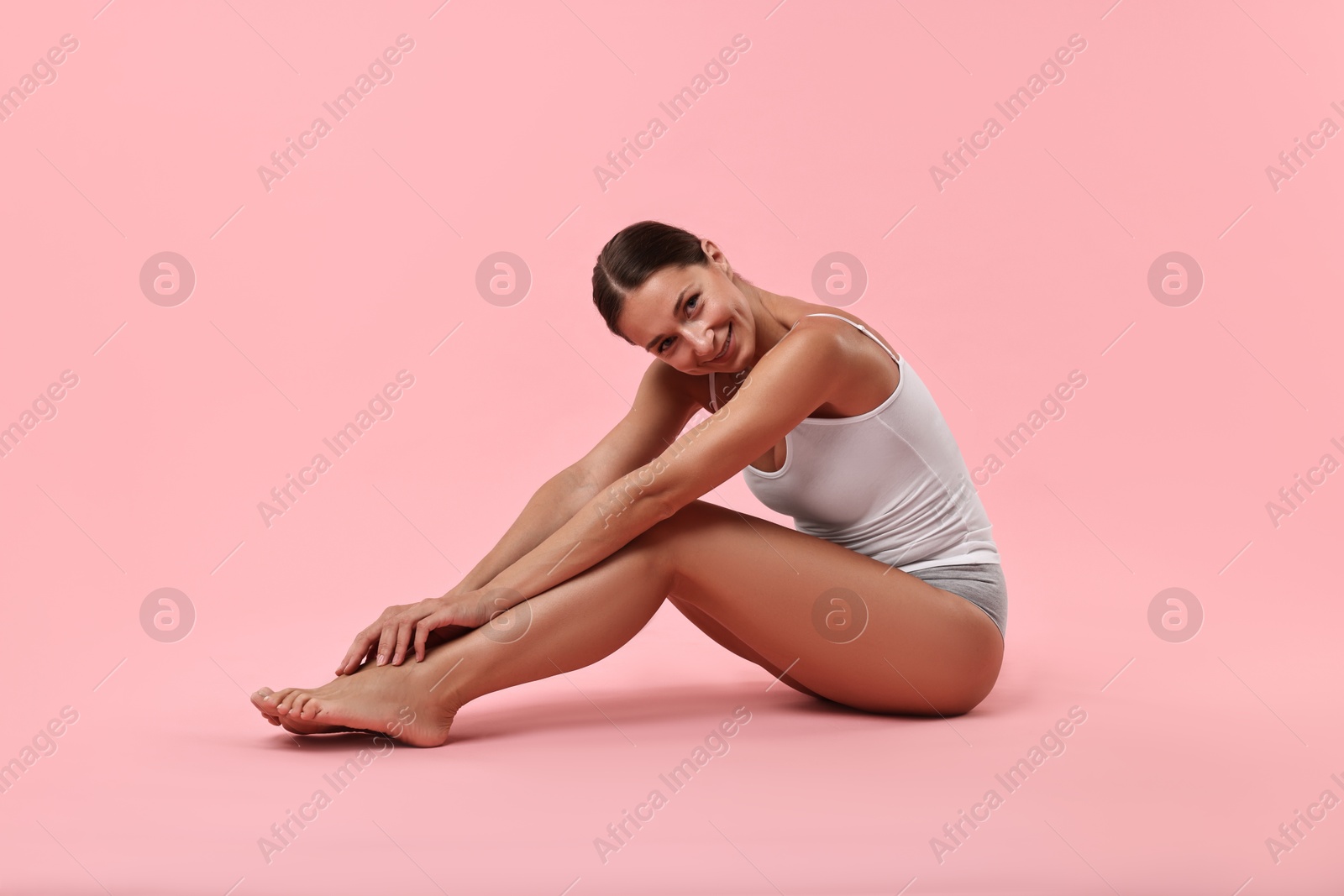 Photo of Smiling woman with perfect skin posing on pink background. Body care