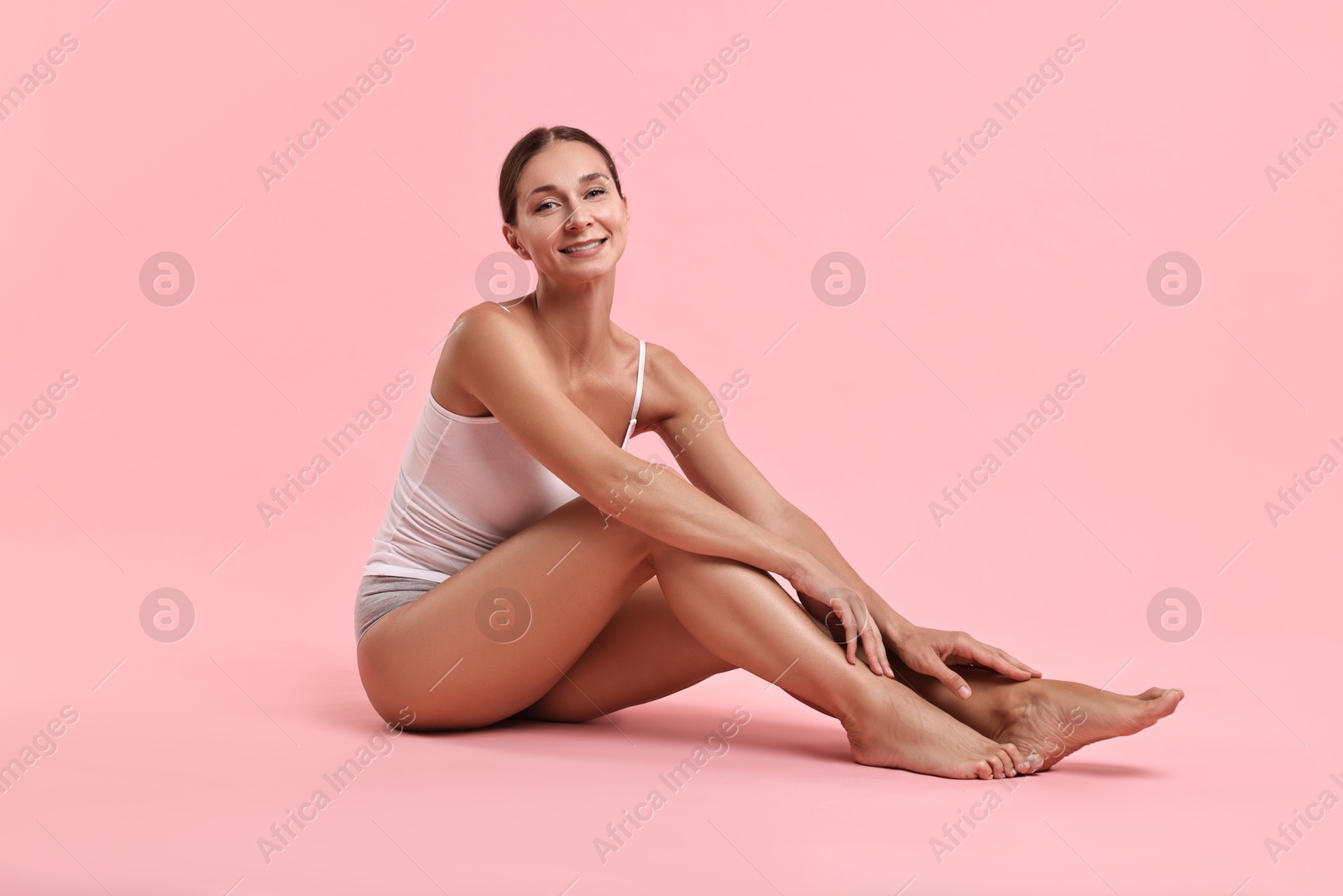 Photo of Smiling woman with perfect skin posing on pink background. Body care