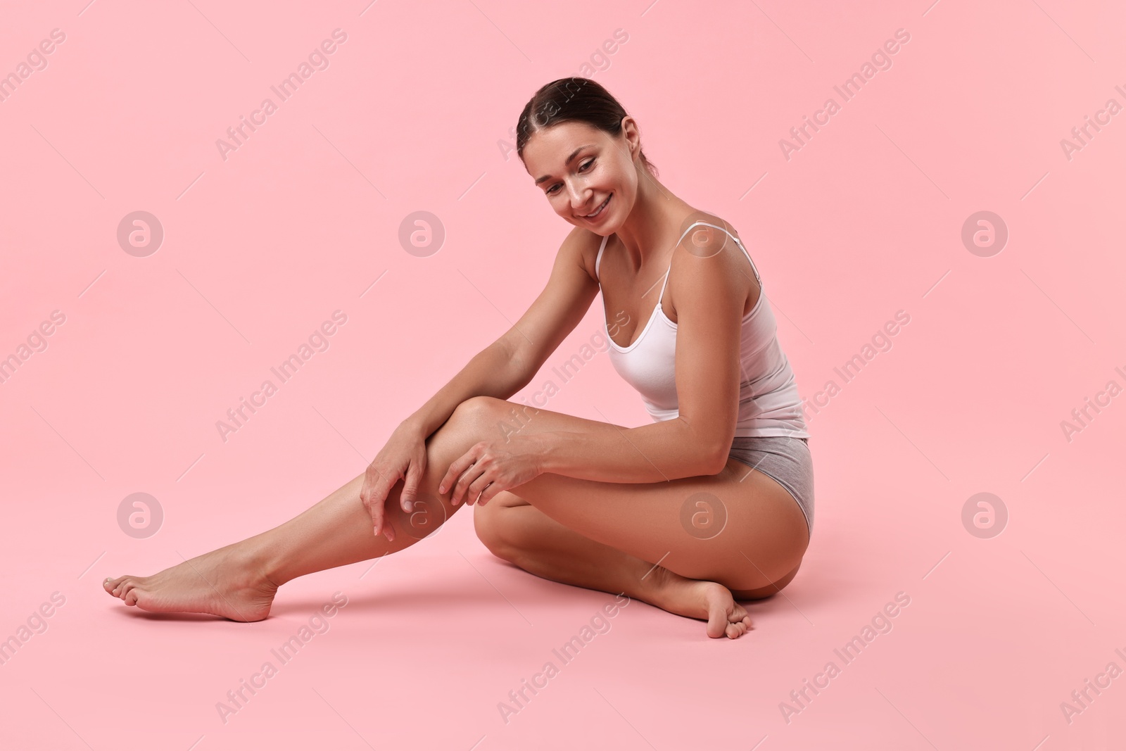 Photo of Smiling woman with perfect skin posing on pink background. Body care