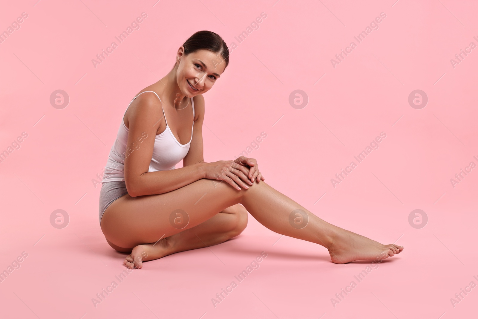 Photo of Smiling woman with perfect skin posing on pink background. Body care