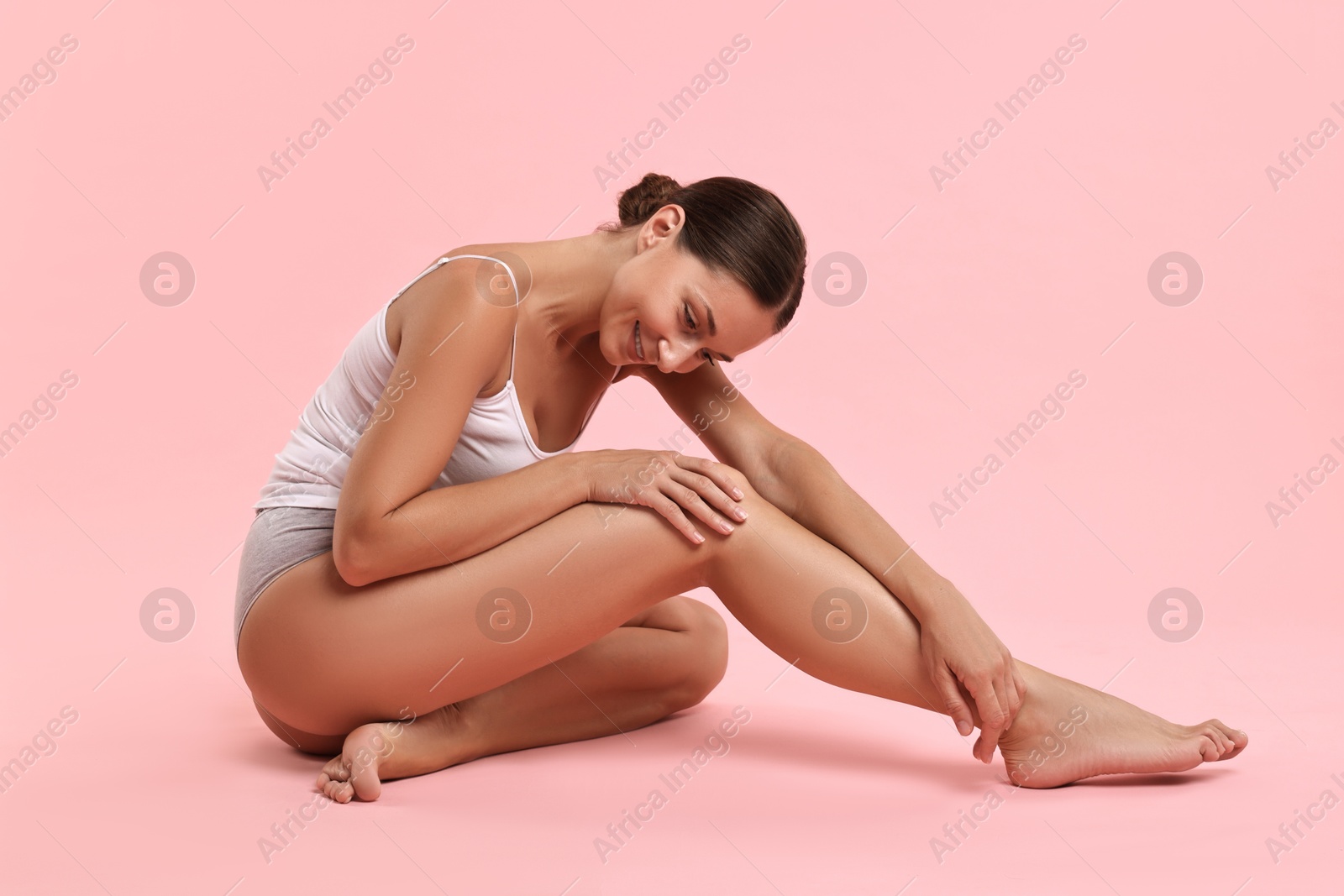 Photo of Smiling woman with perfect skin posing on pink background. Body care