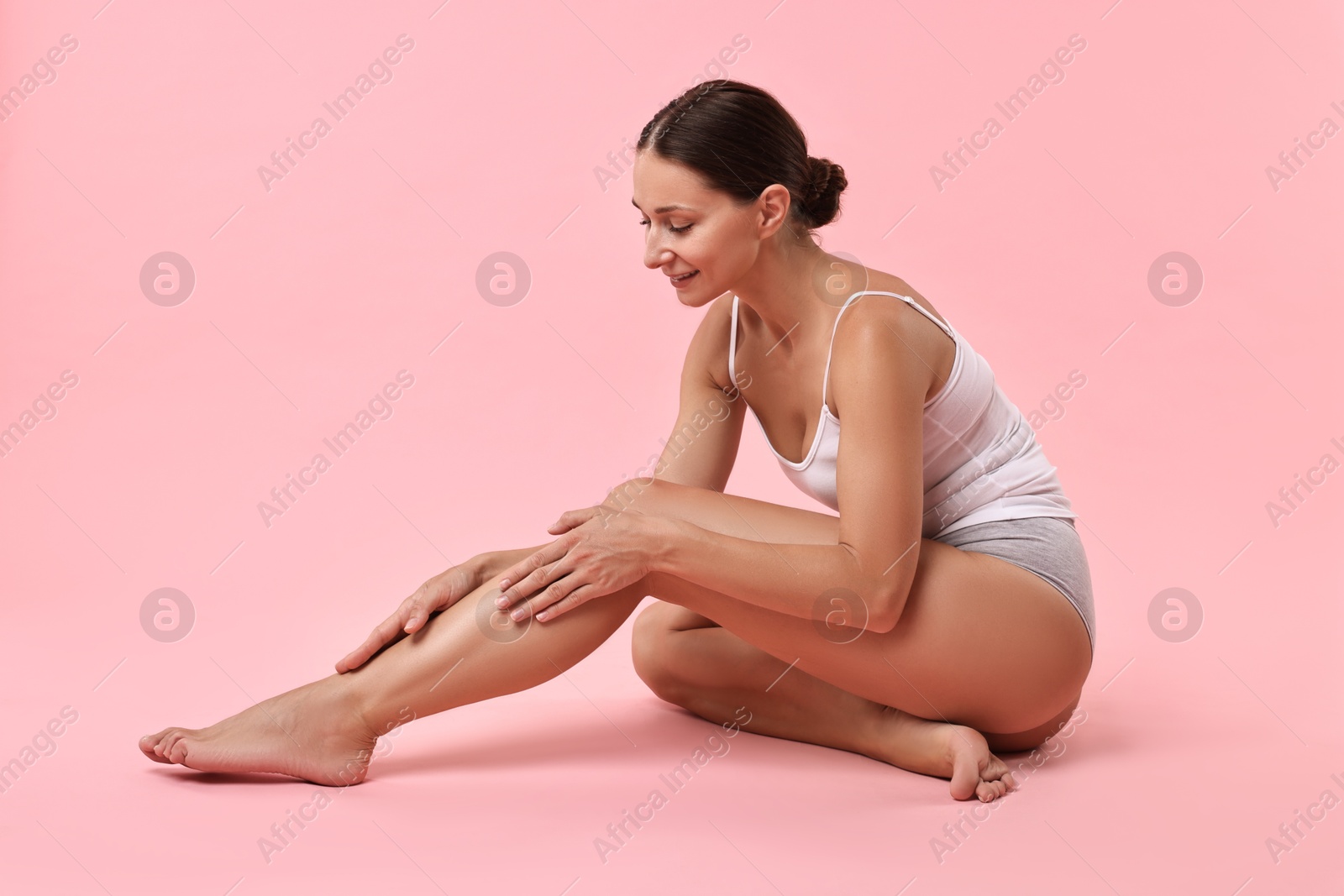 Photo of Smiling woman with perfect skin posing on pink background. Body care