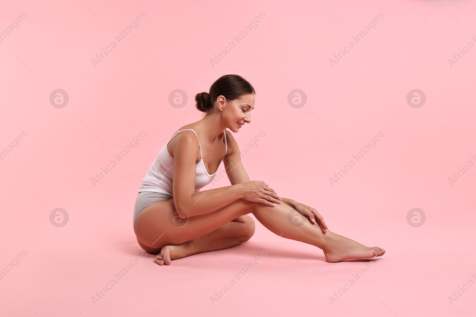 Photo of Smiling woman with perfect skin posing on pink background. Body care