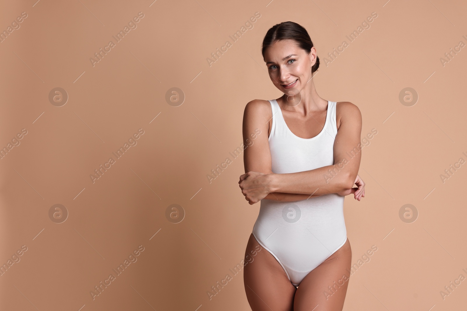 Photo of Smiling woman with perfect skin posing on beige background, space for text. Body care