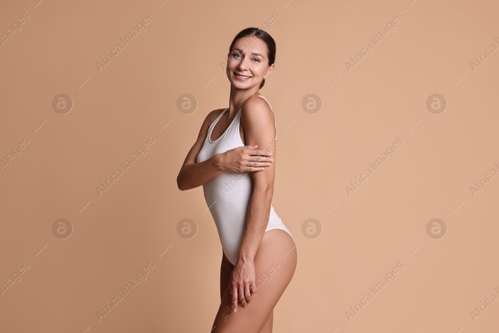 Photo of Smiling woman with perfect skin on beige background. Body care