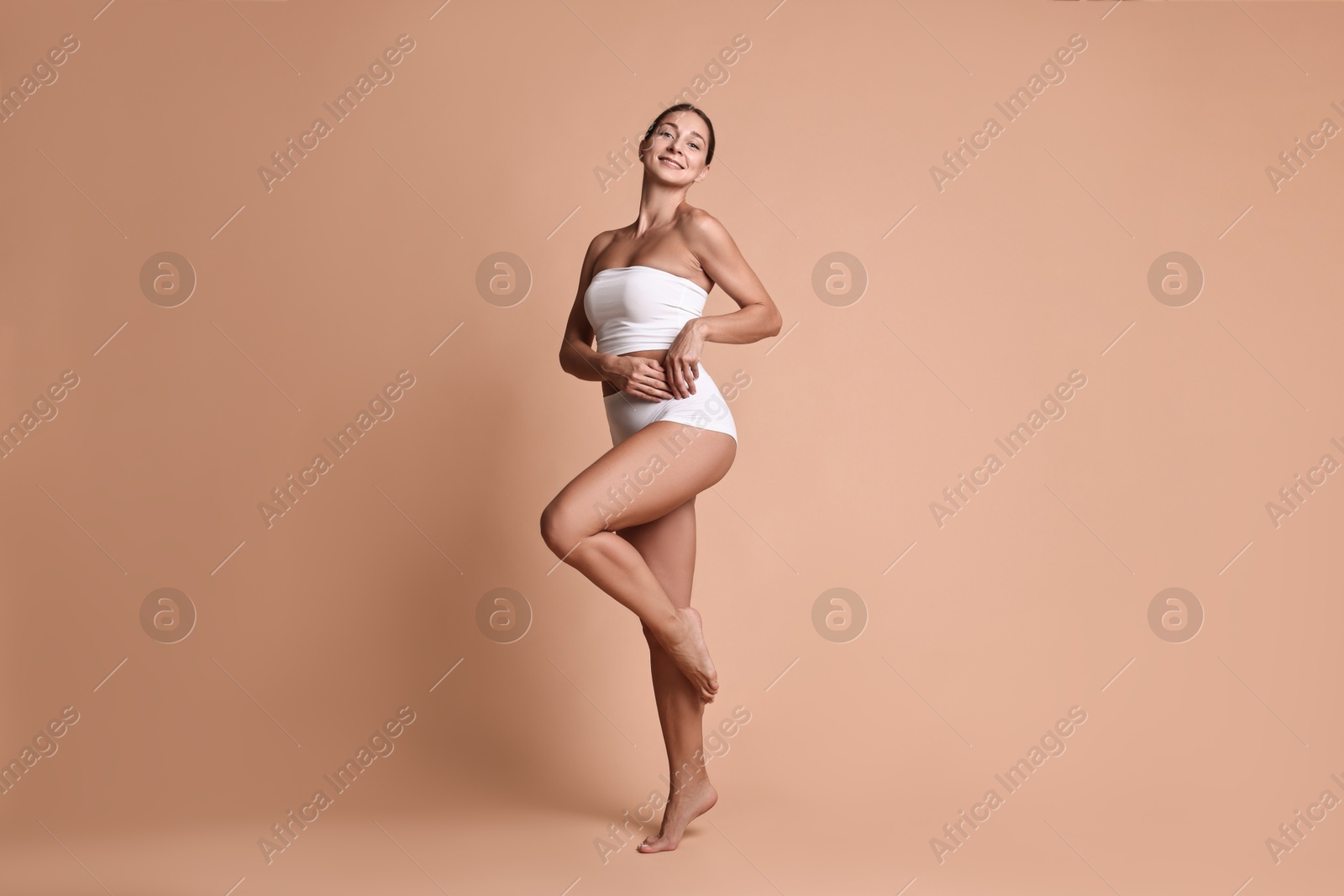 Photo of Smiling woman with perfect skin posing on beige background. Body care