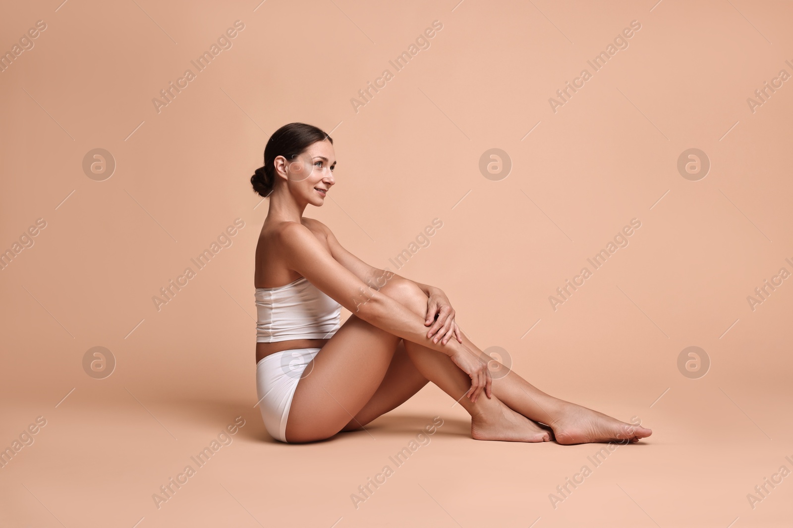 Photo of Smiling woman with perfect skin posing on beige background. Body care