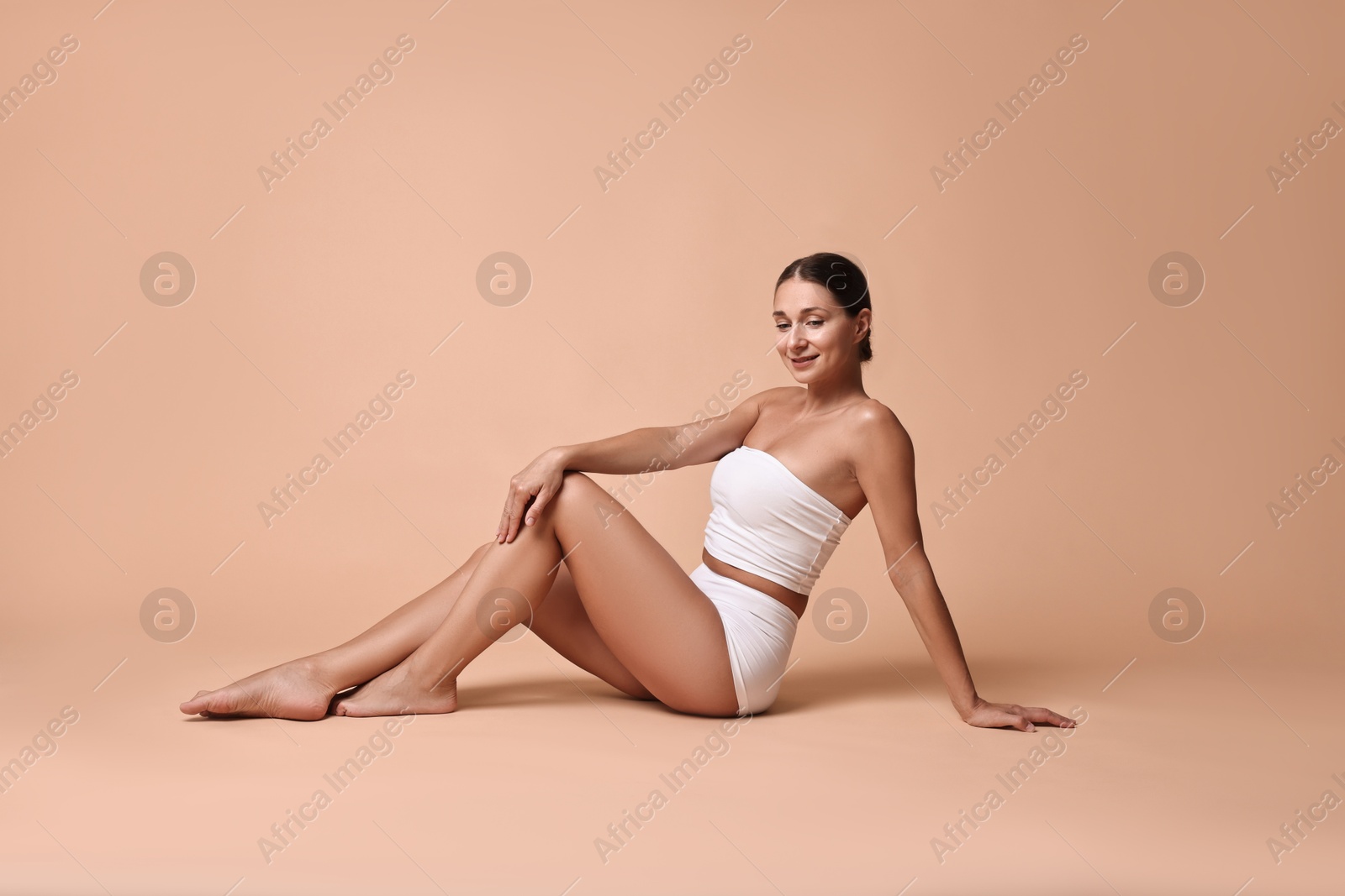 Photo of Smiling woman with perfect skin posing on beige background. Body care