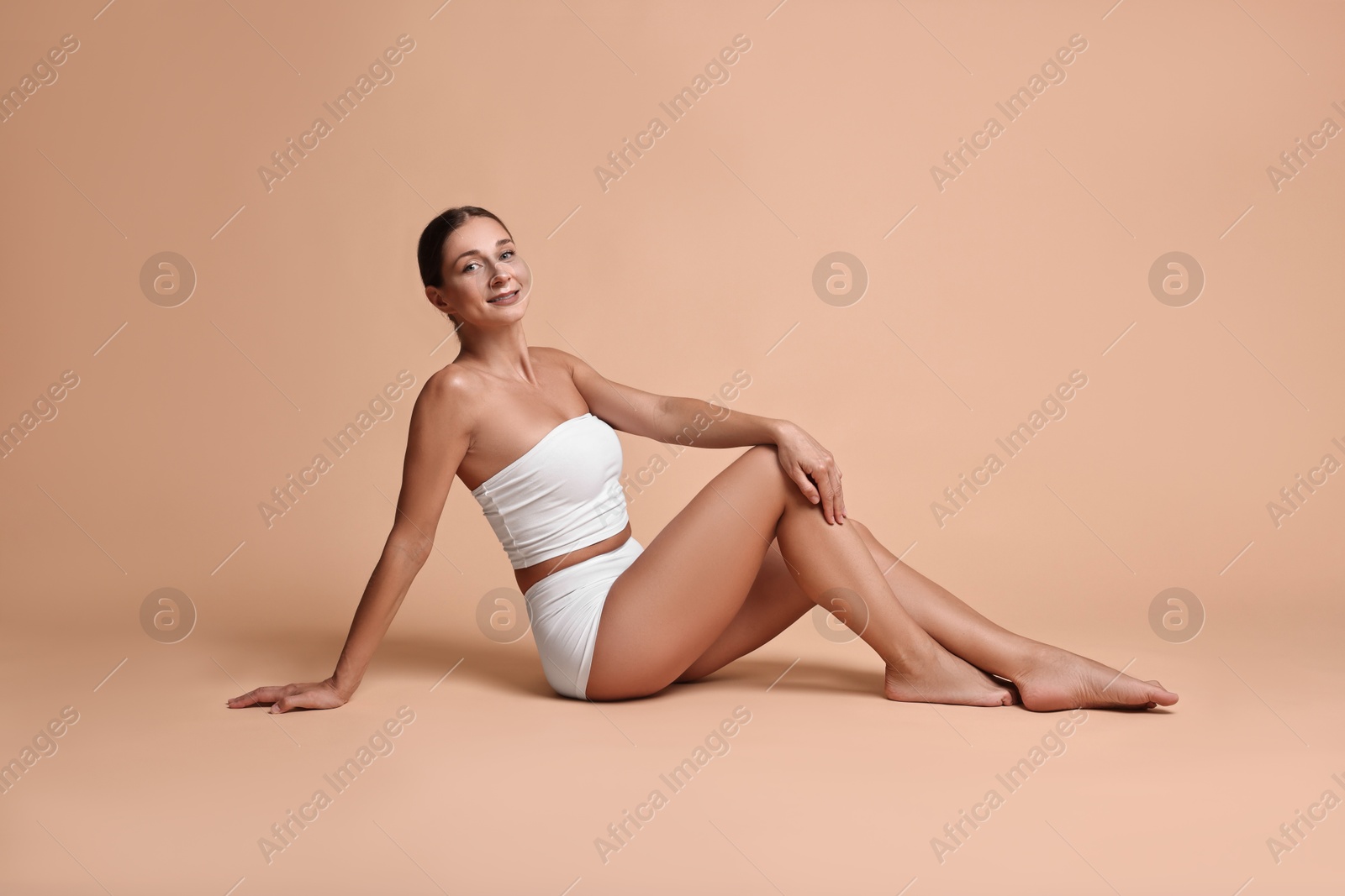 Photo of Smiling woman with perfect skin posing on beige background. Body care