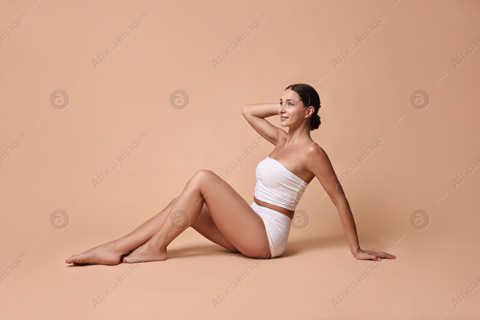 Photo of Smiling woman with perfect skin posing on beige background. Body care