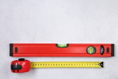 Photo of Building level and measuring tape on grey textured table, top view. Space for text