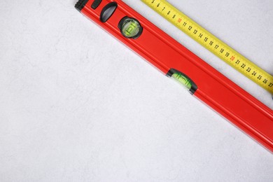 Photo of Building level and measuring tape on grey textured table, top view. Space for text