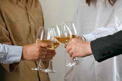 People clinking glasses of wine indoors, closeup